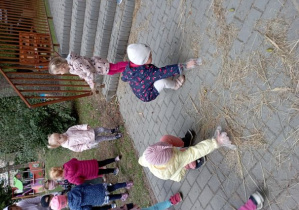 Dzieci zbierają siano porozrzucane w ogrodzie przedszkolnym